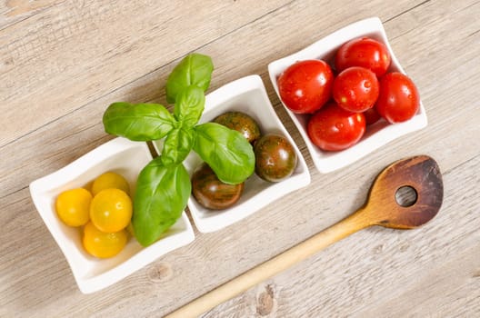 Tomatoes,basil in bowls and wooden spoons