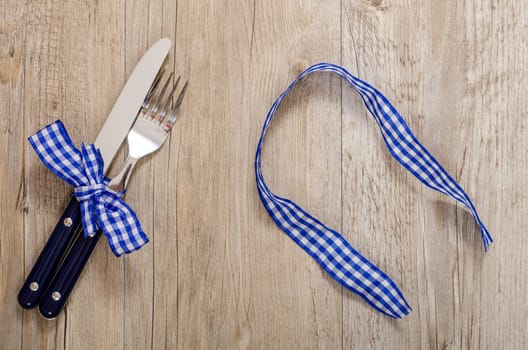 Knife and gable and blue checkered fabric ribbon on a dining table