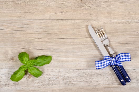 Knife and fork with checkered fabric bow on dining table with text space