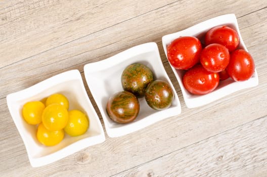 Cochtail tomatoes in yellow,green and red on a wooden board