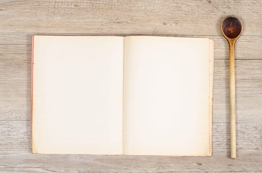 Old paper in a book with a wooden spoon on a wooden table