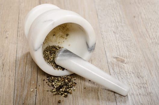 Crushed black pepper in mortar with marble pestle