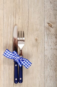 Knife and fork with blue checkered bow in portrait format
