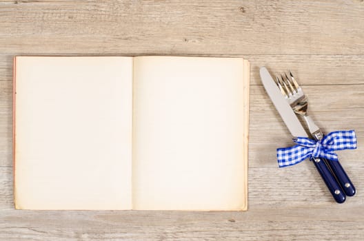 Knife and gable with blue bow and an old book with text space