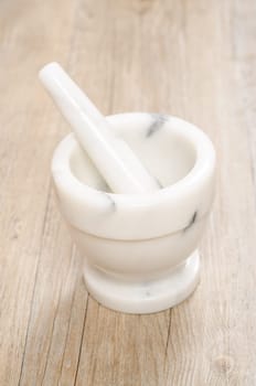 Mortar with pestle on marble on a wooden board