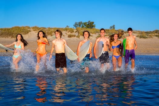 surfer teenagers boys and girls group running happy to the beach splashing water
