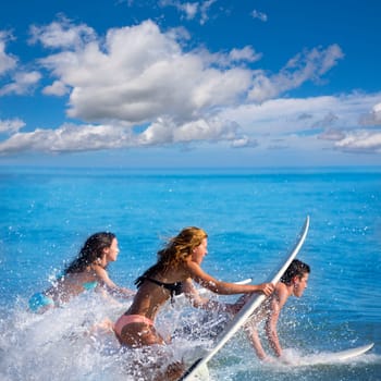 Boys and girls teen surfers running jumping on surfboards at the beach