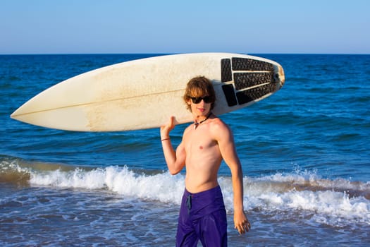 Boy teen surfer happy holing surfboard on the beach shore