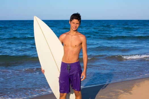 Boy teen surfer happy holing surfboard on the beach shore
