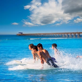 Teenager surfers surfing running jumping on surfboards at Newport pier beach California