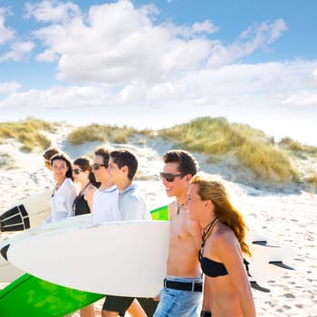 Surfer teen boys and girls group walking on beach sand