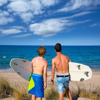 Boys teen surfers rear back view looking at beach from uo dune