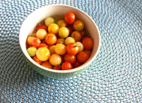 Multi-colored cherry tomatoes in a bowl on a blue mat