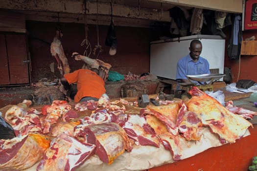 KAMPALA, UGANDA - SEPTEMBER 29 2012. Two African men work and prepare meat in a dirty open air market in Kampala, Uganda on September 28,2012.