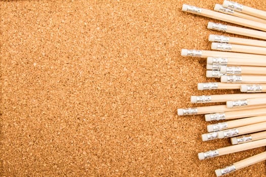 Bunch of wooden pencils over a cork board.