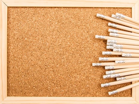 Bunch of wooden pencils over a cork board.