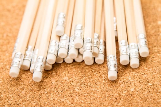 Bunch of wooden pencils over a cork board.
