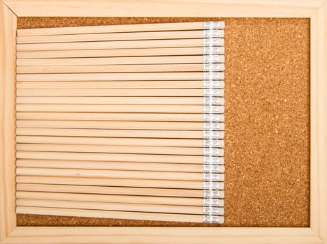 Bunch of wooden pencils over a cork board.