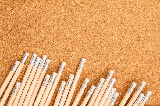 Bunch of wooden pencils over a cork board.