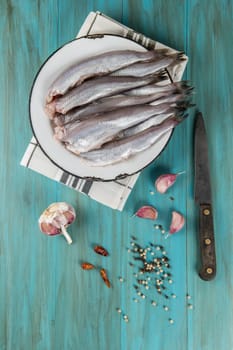 A plate with fish on the kitche table and ingredients to cook it.