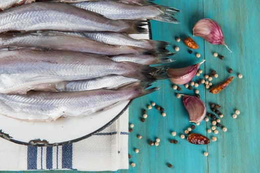 A plate with fish on the kitche table and ingredients to cook it.