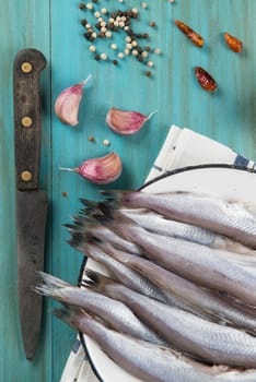 A plate with fish on the kitche table and ingredients to cook it.