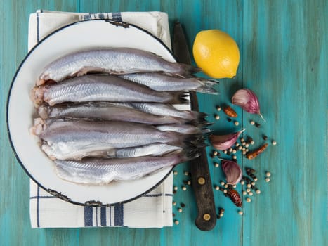 A plate with fish on the kitche table and ingredients to cook it.