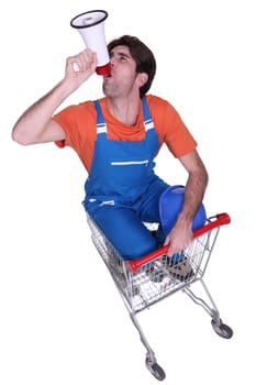 Builder with megaphone sat in shopping trolley