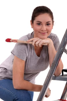 Woman with paint brush leaning on a ladder
