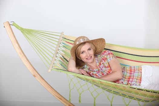 Studio shot of a woman in a straw hat lounging on a striped hammock