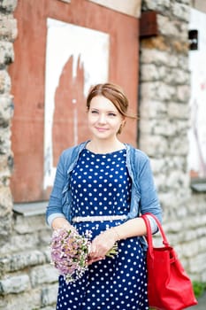 Smiling woman in dress hold bundle of flowers