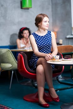 Woman in white spotted dress sit in cafe