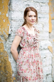 Woman in flowered dress rests on stone wall