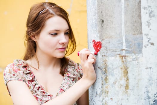 Woman in flowered dress draw heart on wall