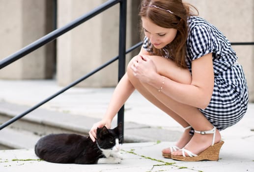 Woman in blue checkered dress fondle street cat