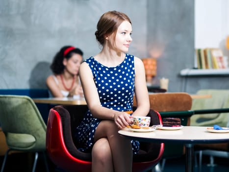 Zoomed woman in spotted dress sit in cafe