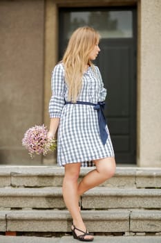 Woman in checkered dress hold flowers at hand