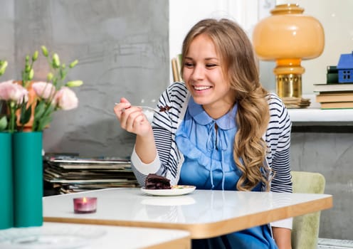 Woman at blue dress tasting cake with fork