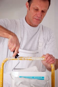 Man dipping a paint roller into a can of paint