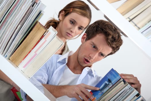 Man looking at a selection of books in shock