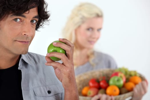 Man with apple and woman with basket in the background