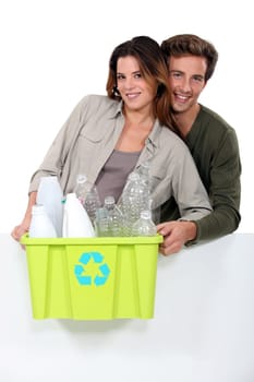 Smiling couple sorting garbage on white background