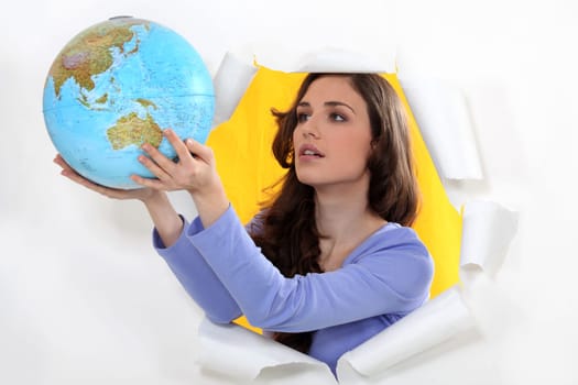 Woman getting out of hole with globe