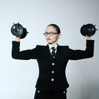 studio shot portrait of one caucasian young bsuiness woman holding weights