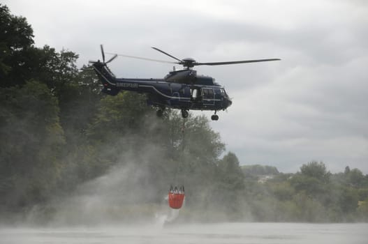 Fire-fighting helicopter picks up water