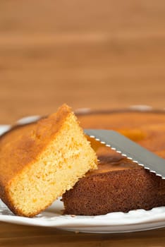 A cut homemade cake showing its texture on a wooden surface.