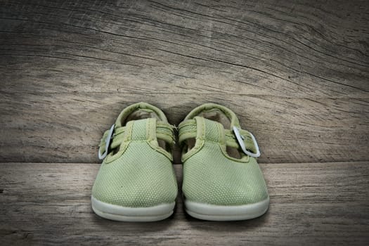 Green shoes for baby on an old wooden shelf