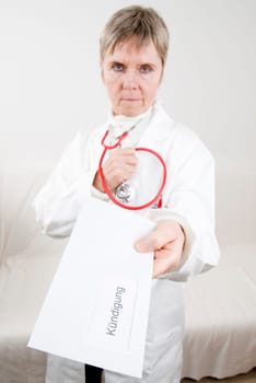 elderly doctor hands over her resignation in an envelope with a serious look towards the camera