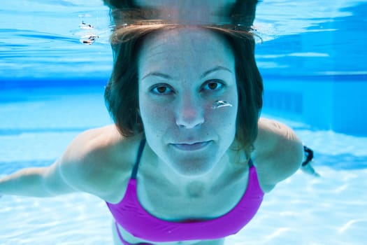 Closeup of female swimmer underwater in swimming pool with eyes open