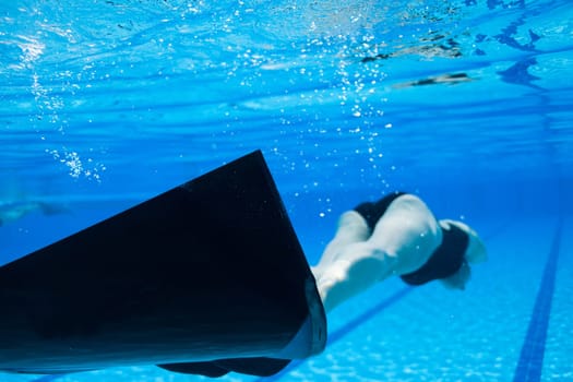 Female freediver with monofin swimming underwater in swimming pool